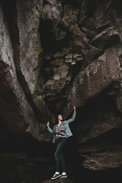 a young person standing on the side of a large rock