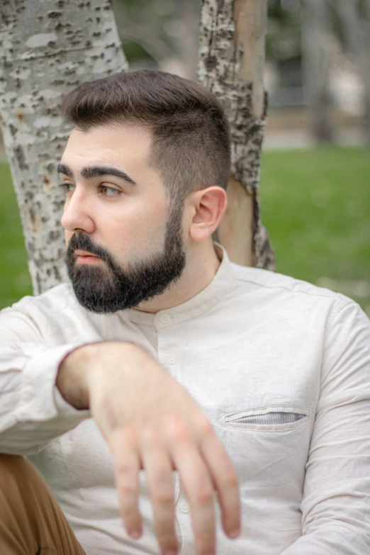 a man sitting against a tree in a park