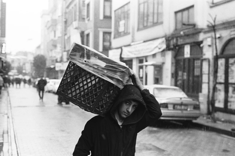 a man in a jacket walking down the street carrying a basket