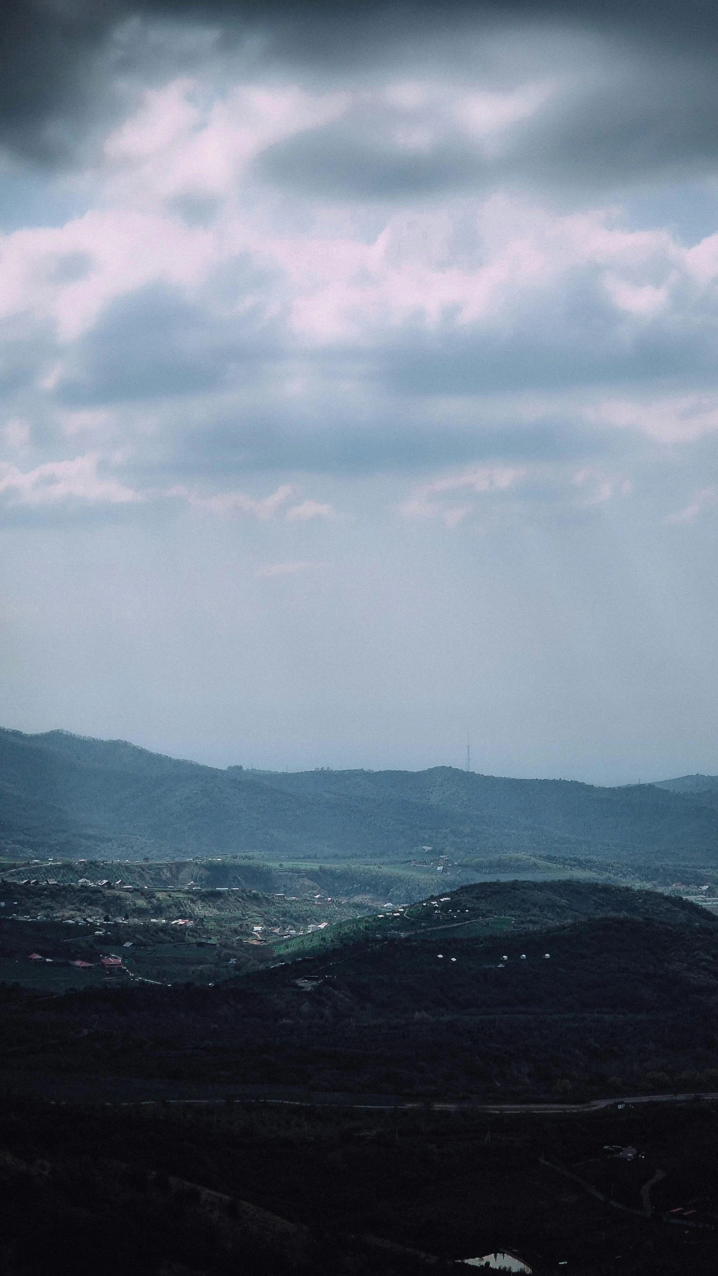 an airplane is flying over the hills under a cloudy sky