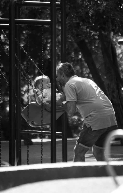 an old man is playing on a swing in the park