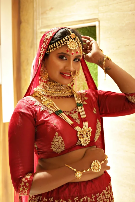 the indian woman is wearing a red and gold wedding outfit