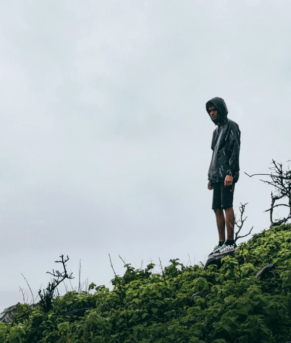 man standing on a green hillside on a cloudy day