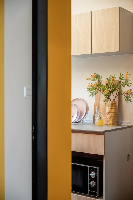 a yellow kitchen counter with a brown vase full of flowers