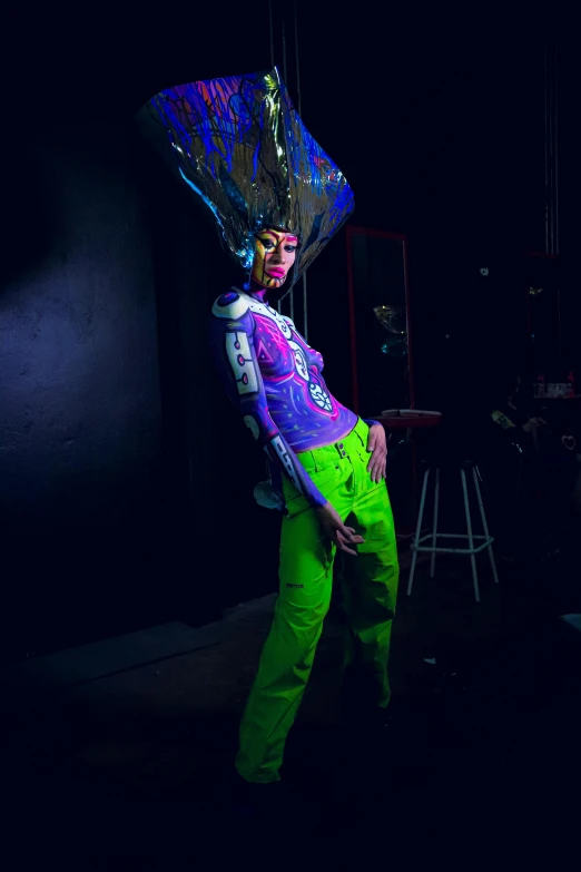 a man in neon colored clothing stands next to a wall with a light on it