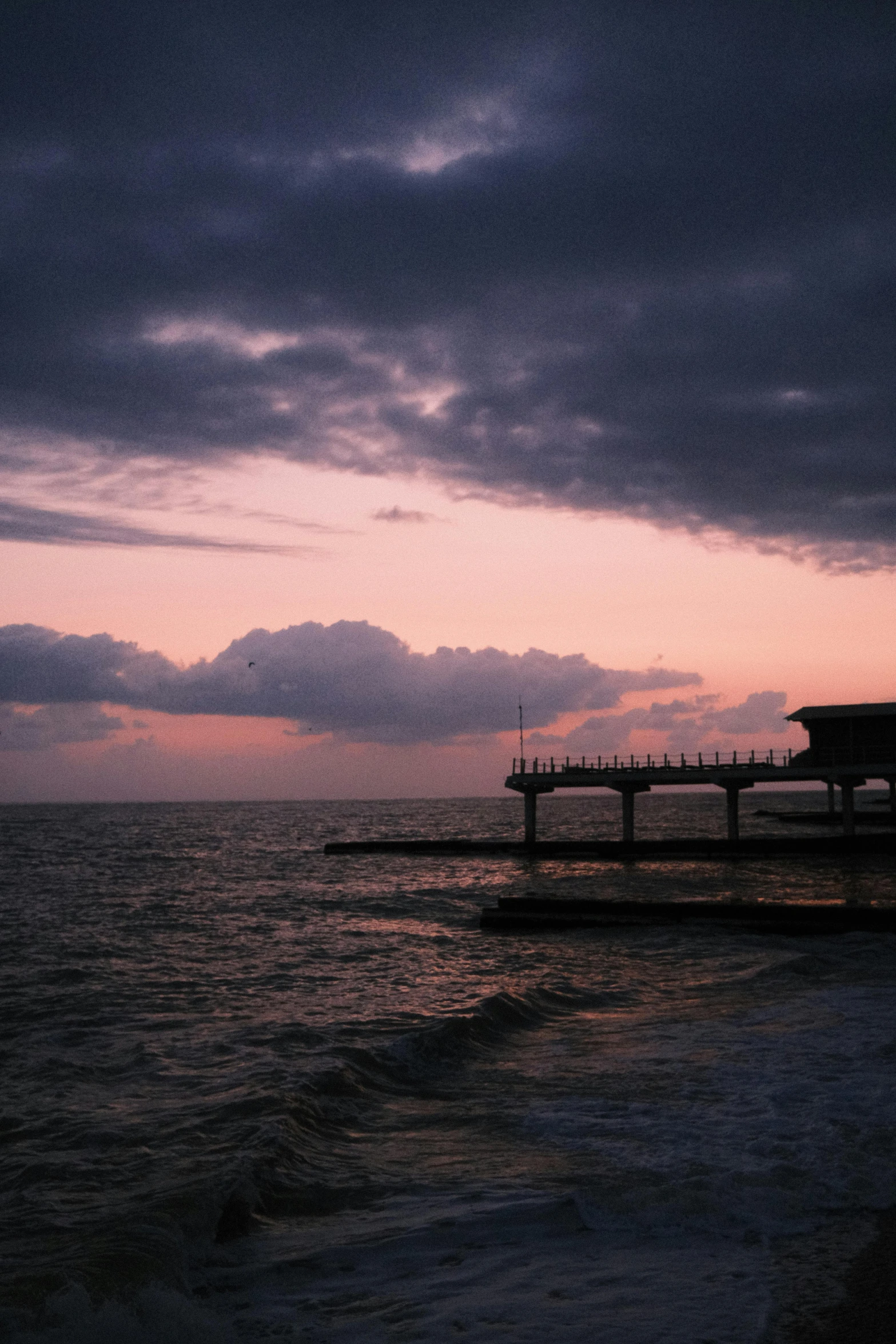 a dark sky and a pier in the ocean