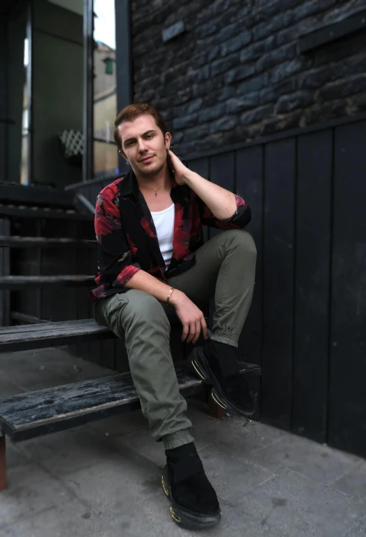 a young man sits on a bench in front of a building