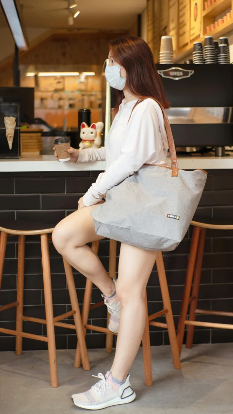 a woman in grey holding a gray bag