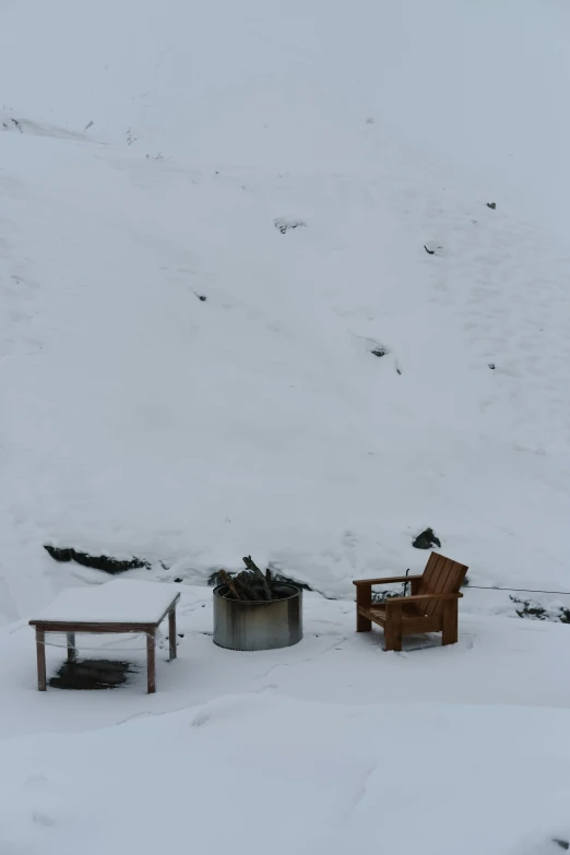 a chair and table covered with snow on a snowy mountain