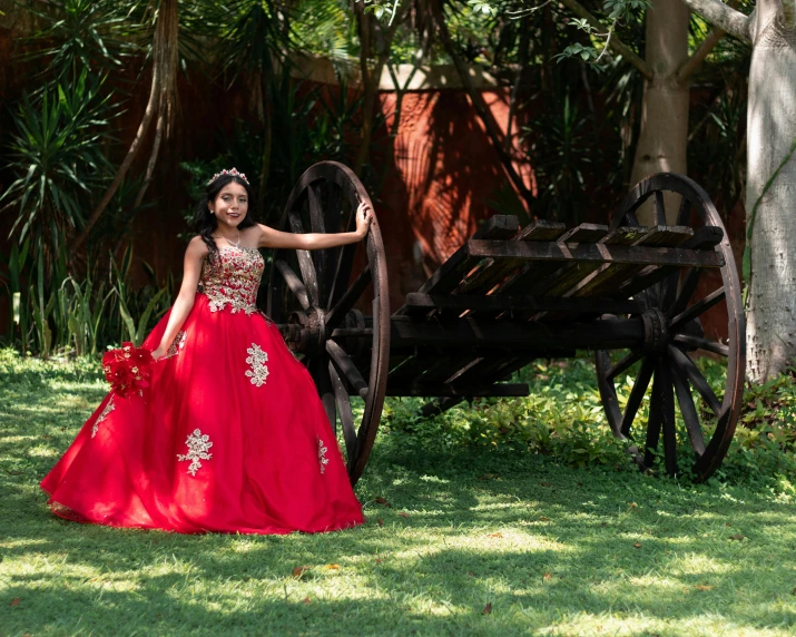 a woman in a red dress leaning against an old fashioned carriage