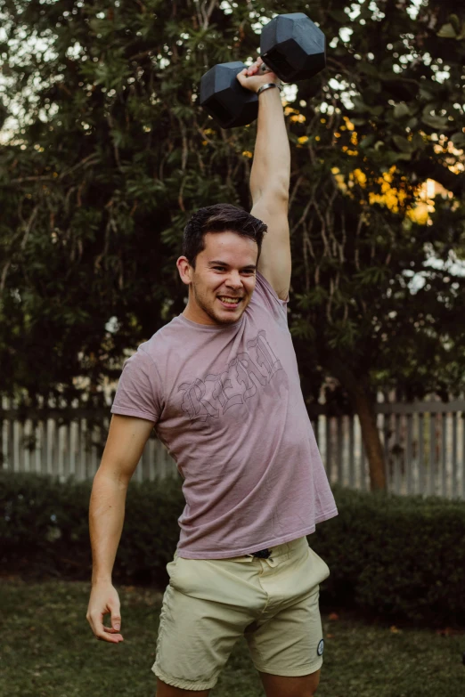 a young man lifting two black dumbbells to the side