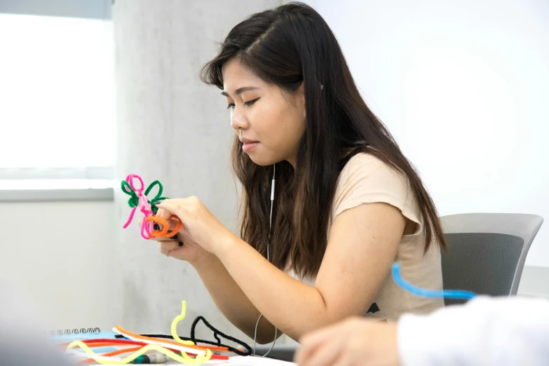 woman playing with colorful string art in front of laptop