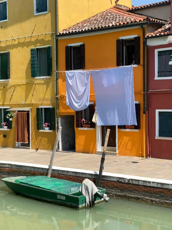 a row of buildings line the side of the water with clothes hanging off