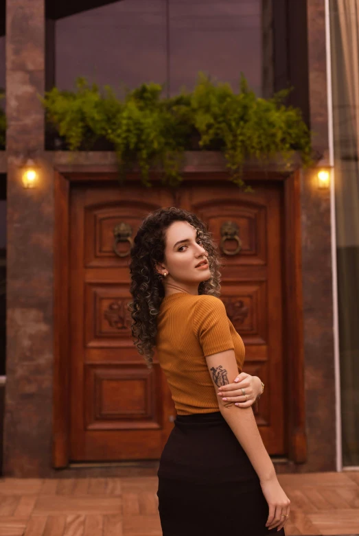 a woman in a skirt and shirt is standing in front of a door