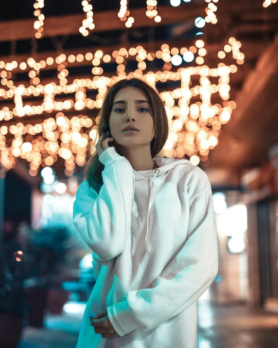 young asian woman in white sweater and hoodie looking at the camera