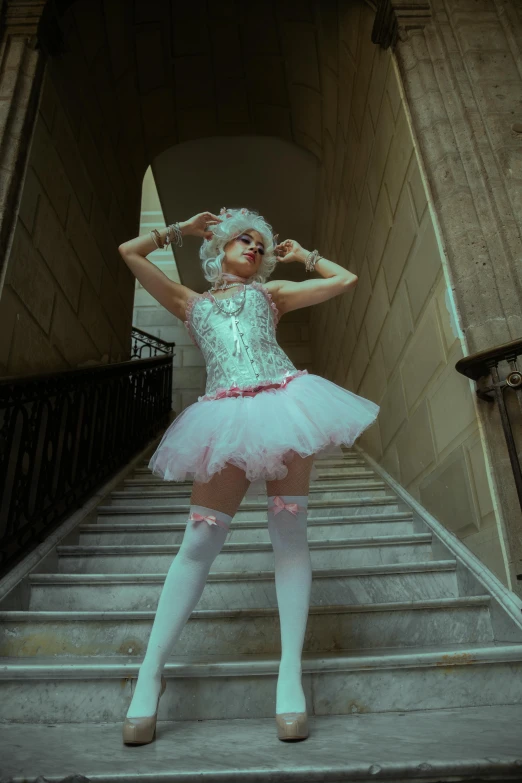 a woman wearing white clothing standing in front of stairs