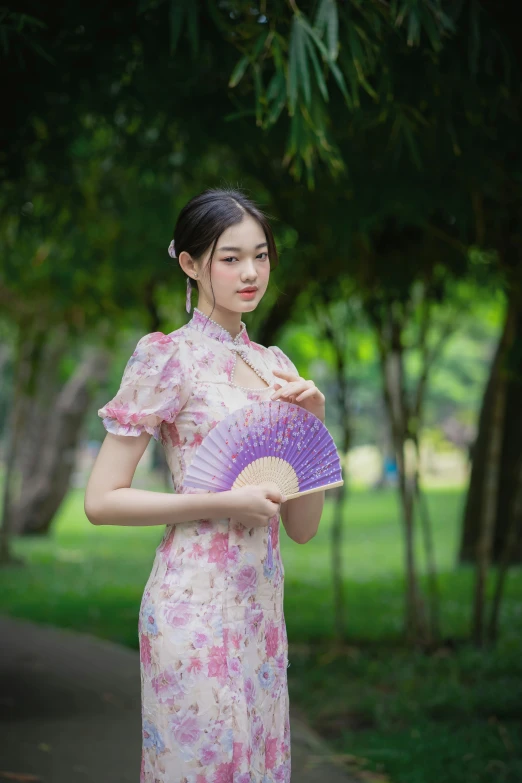 a woman in a long floral dress with a fan