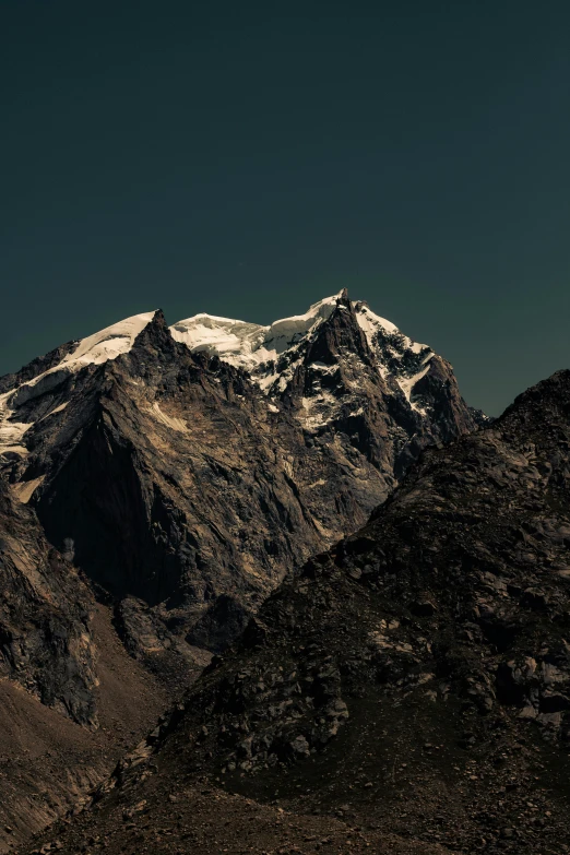 a mountain range with mountains behind it and a clear sky in the background