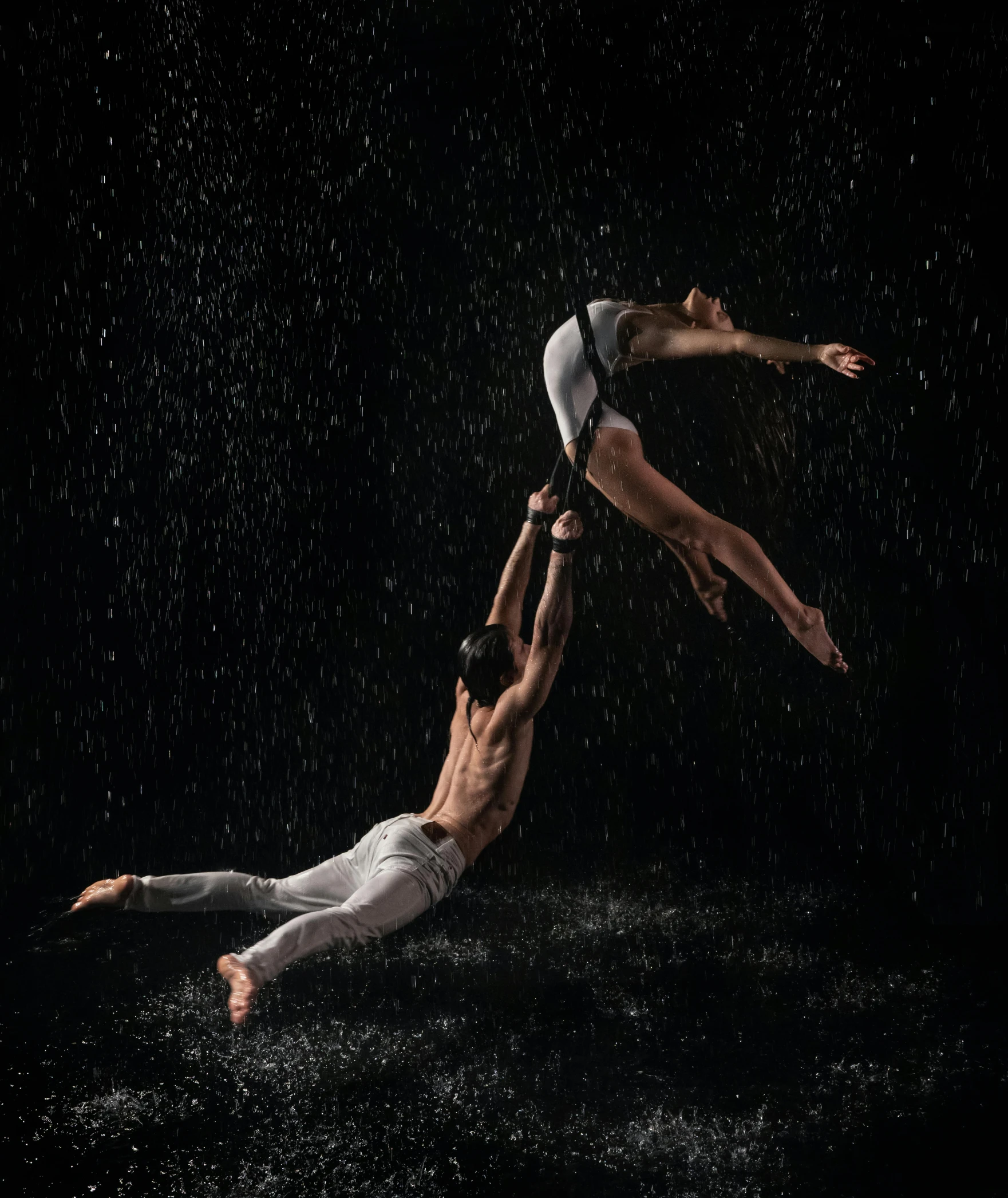 three men are doing a aerial acrobatic maneuver in the rain