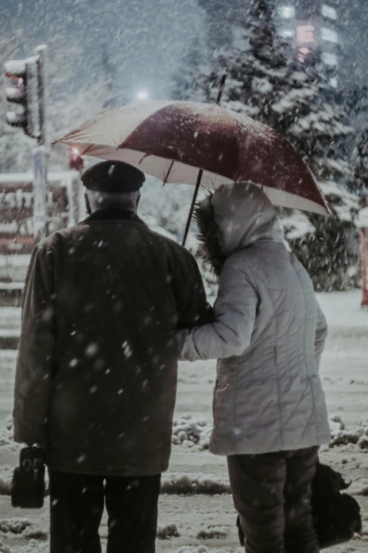 two people are walking down the street in the snow