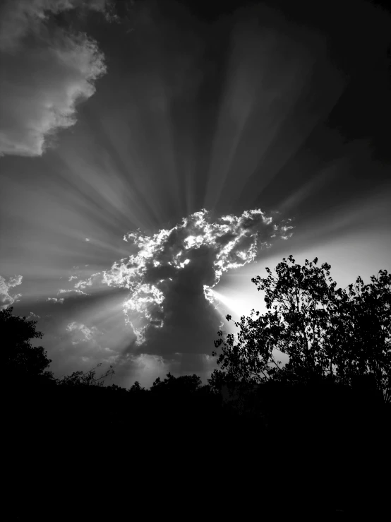 the sun shining through clouds above some trees