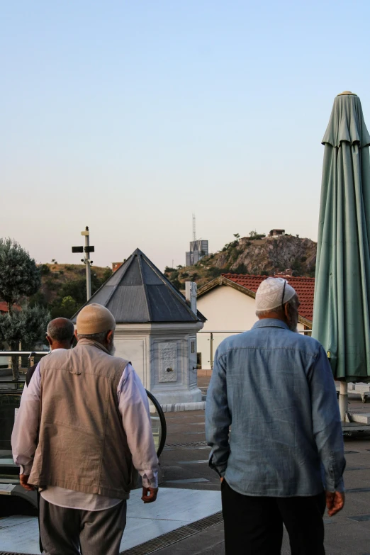 two men walking away from the camera, one is carrying a cane