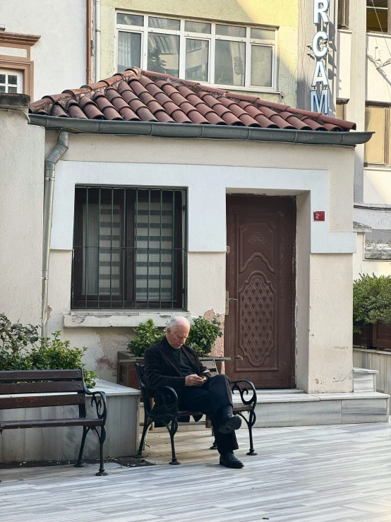 a man sits on a bench outside his house