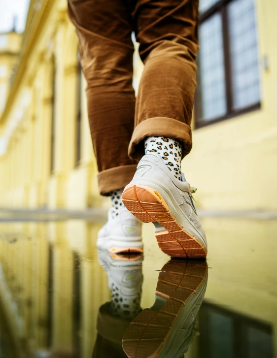 a man's legs, wearing sneakers on a mirrored surface