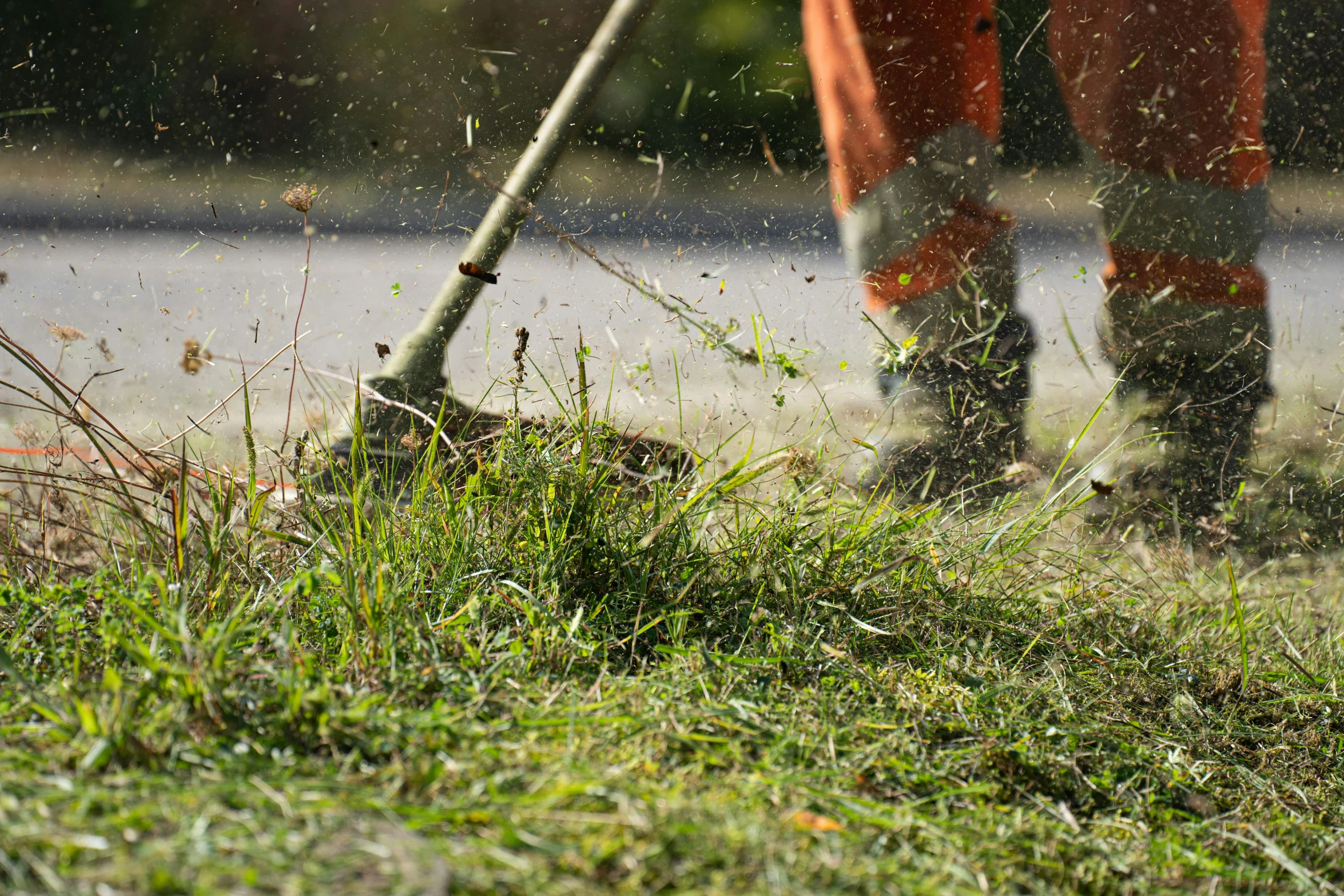 a man in boots using a garden sprinkle to mow grass