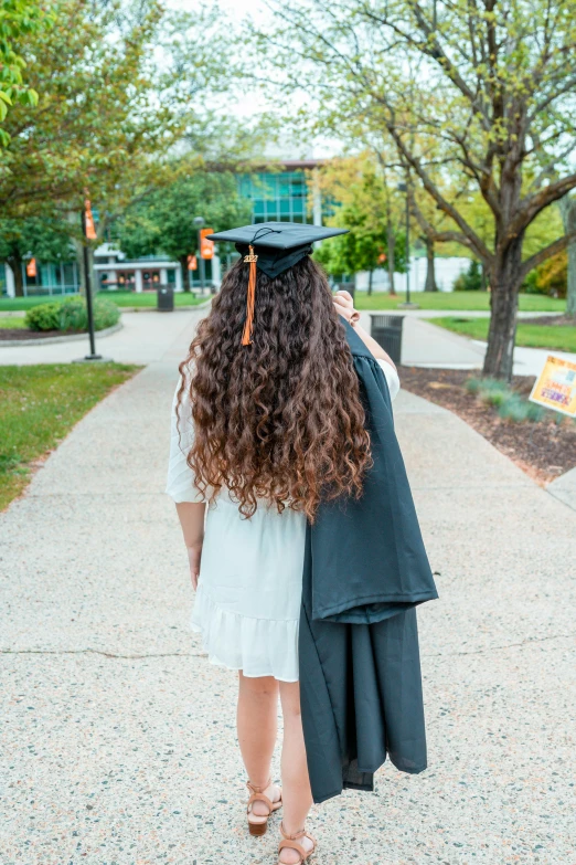 a girl wearing her cap and gown walking down a sidewalk