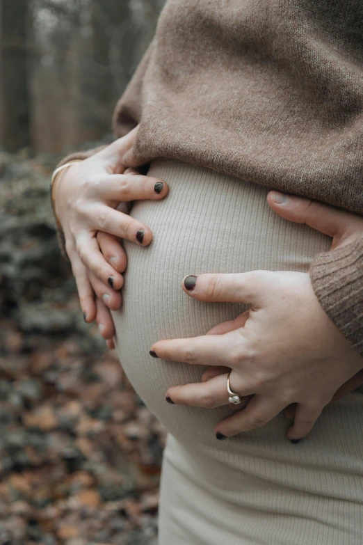 a pregnant woman's belly is shown with her hands on her belly