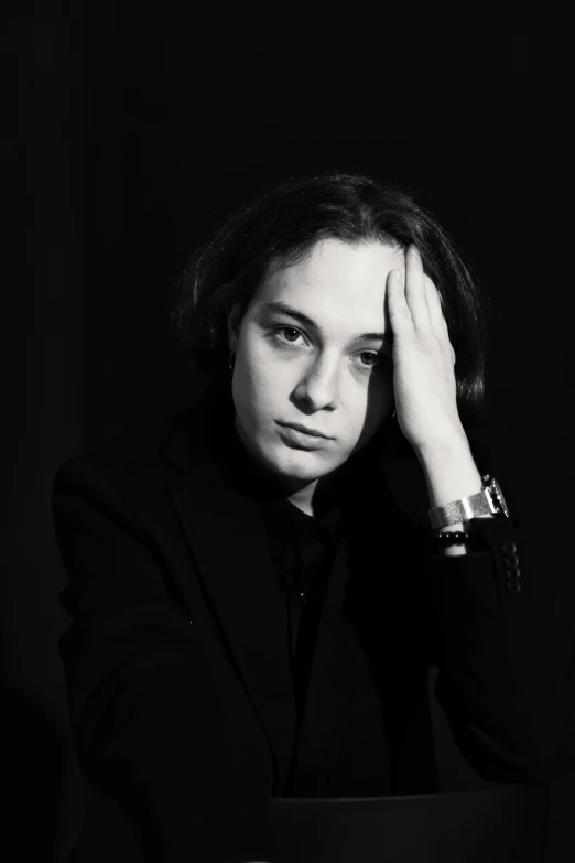 a young woman sitting in front of a table while holding her head in front of her