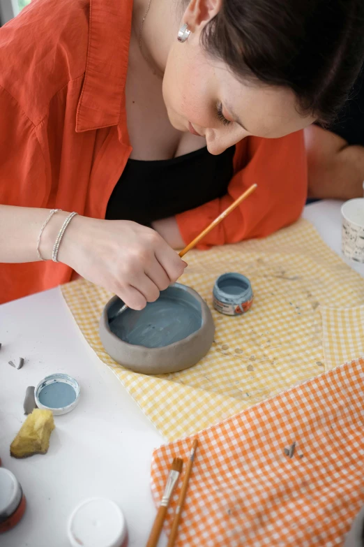 a woman is painting pots on a table