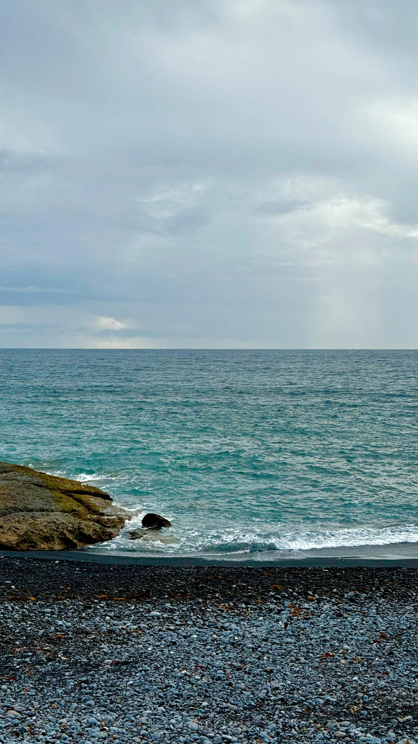 two people standing on the rocks and the ocean