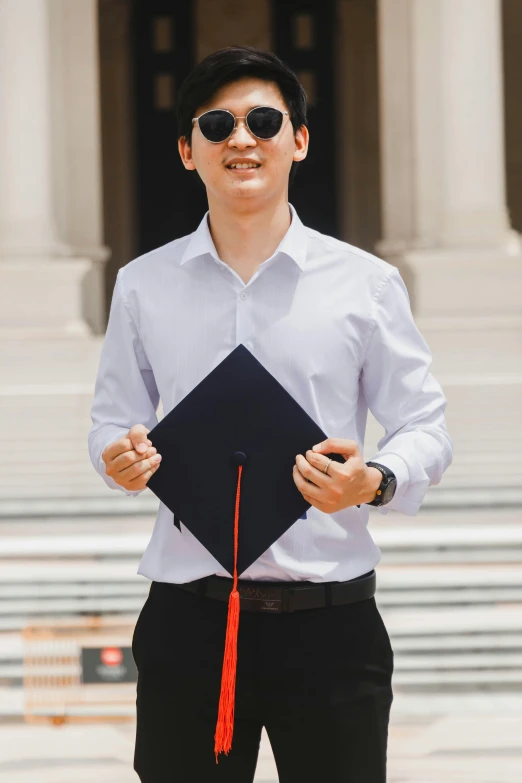 the graduate poses for his picture with a piece of red paper