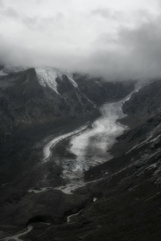 a river with snow covered mountains and clouds