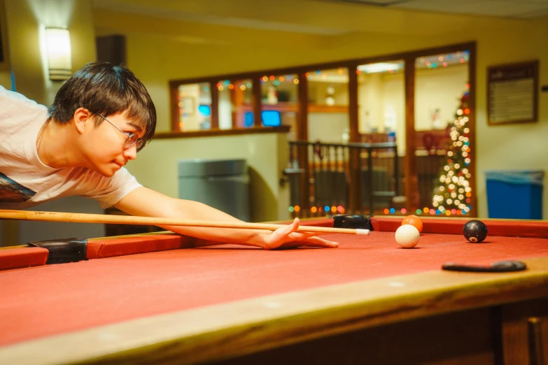  leaning over pool table preparing to hit cues