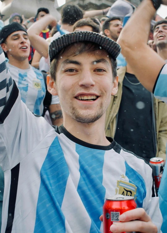 a man with a hat holding up a red and black cup