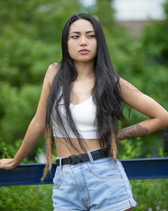 young woman wearing blue jean shorts with her arms behind her head