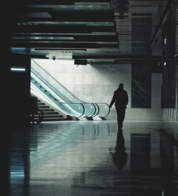 person walking in a tunnel toward an escalator with an escalator behind them