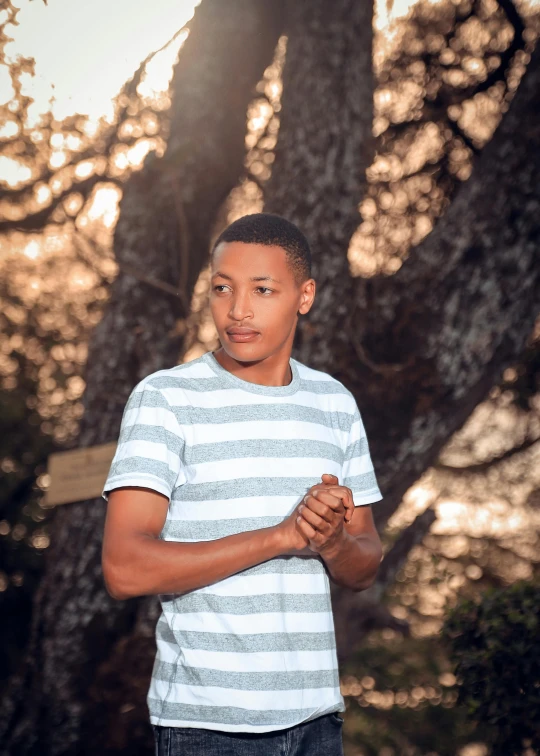 a young man is smiling in front of a tree