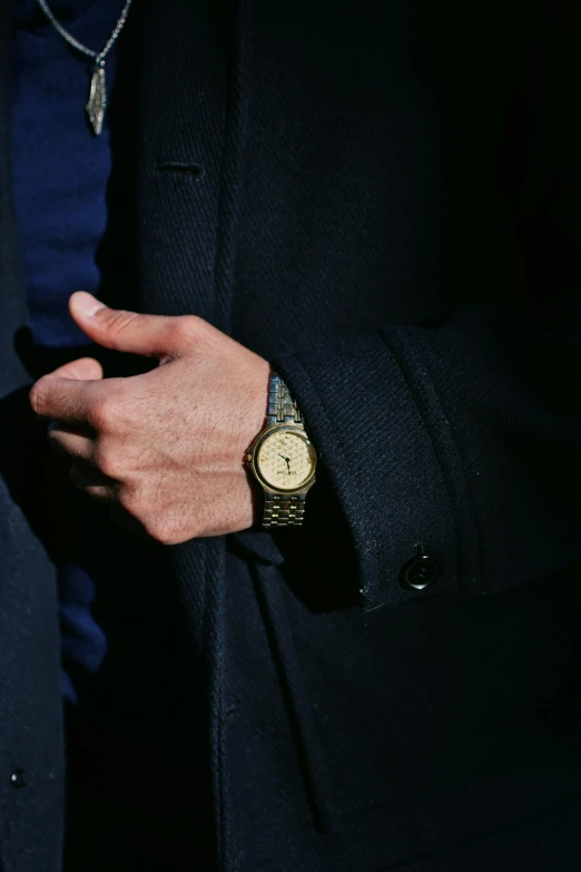 a man wearing a gold and black watch is holding his hand