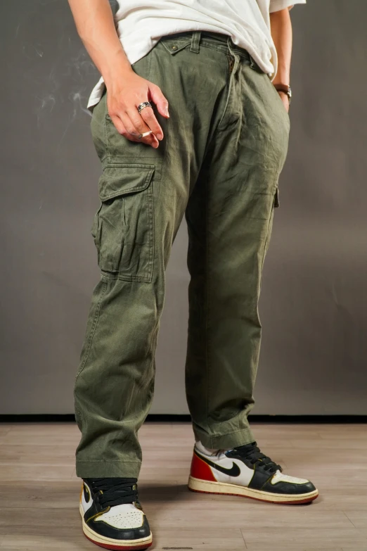 there is a man standing on a wood floor wearing green pants