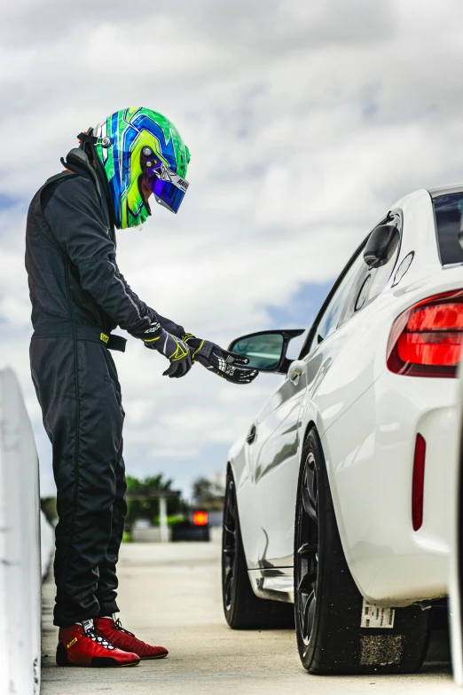 the man is near a parked car with his helmet on