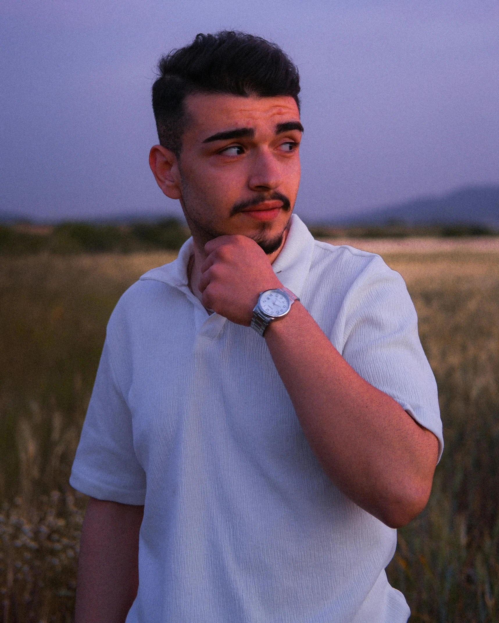 a man standing in a field wearing a watch
