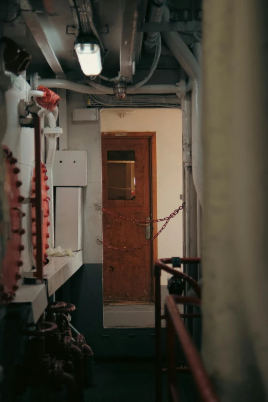 the room has wood door and pipes on the ceiling