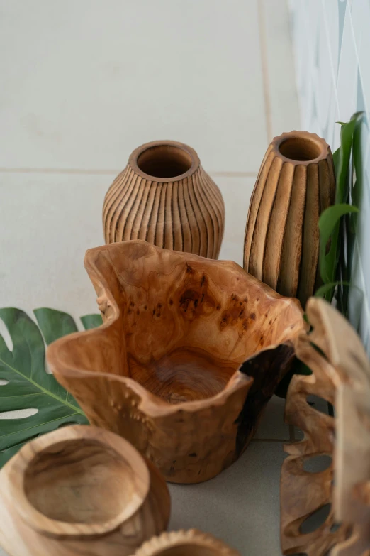 several wooden vases and bowls next to some leaves