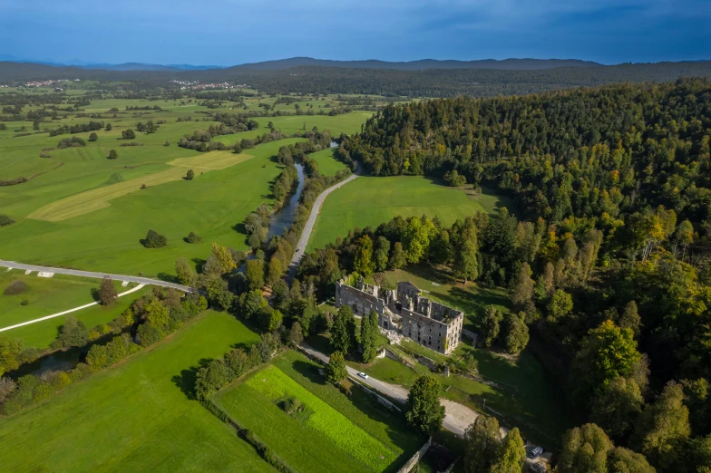 an aerial view of an estate surrounded by greenery and a small stream