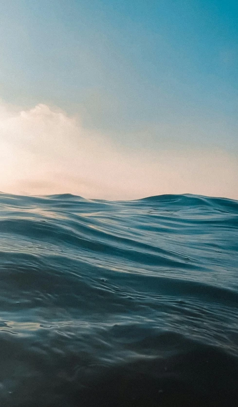 a view of the blue ocean with a lone wave