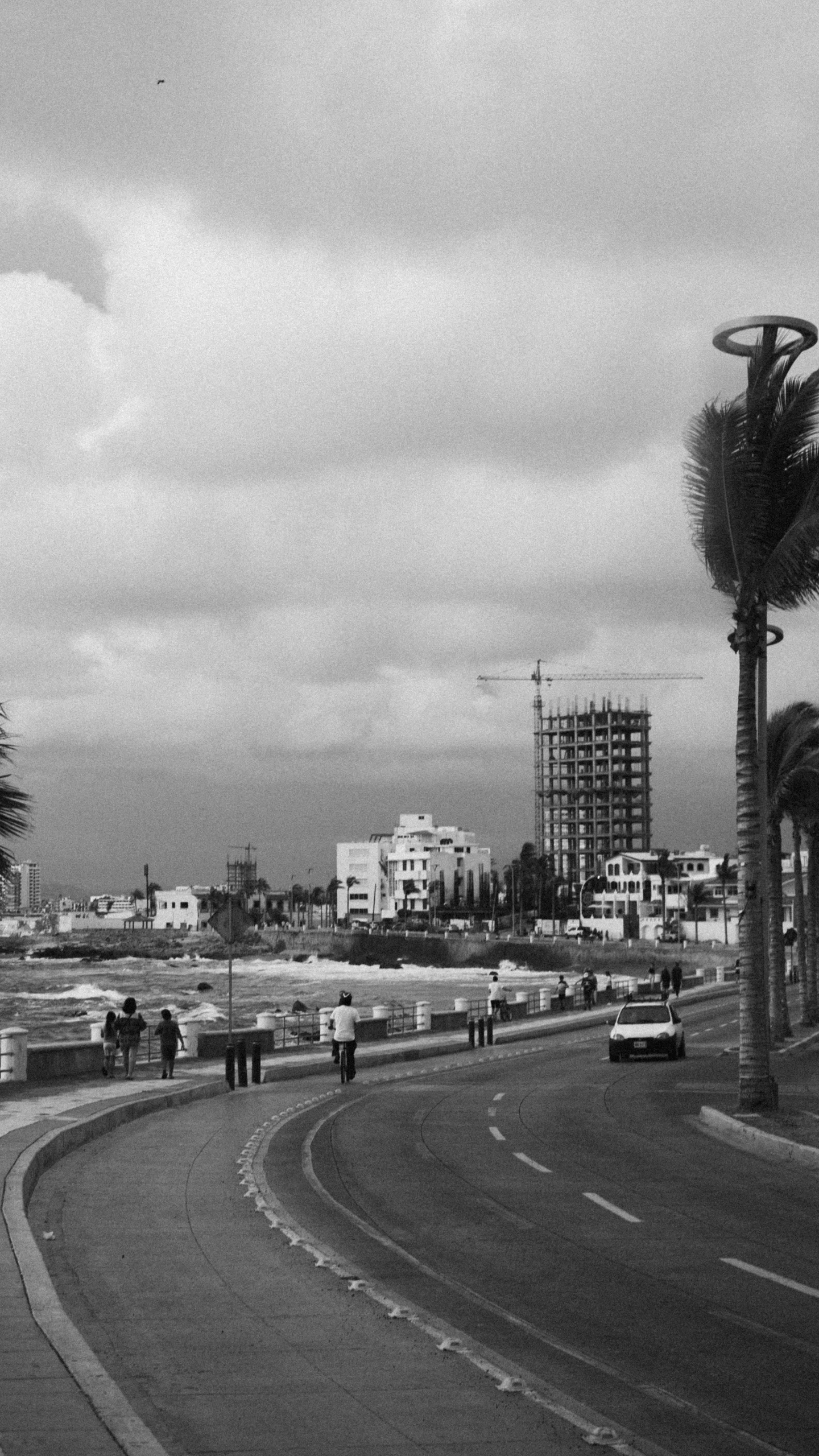 a few people walk down the road towards the beach